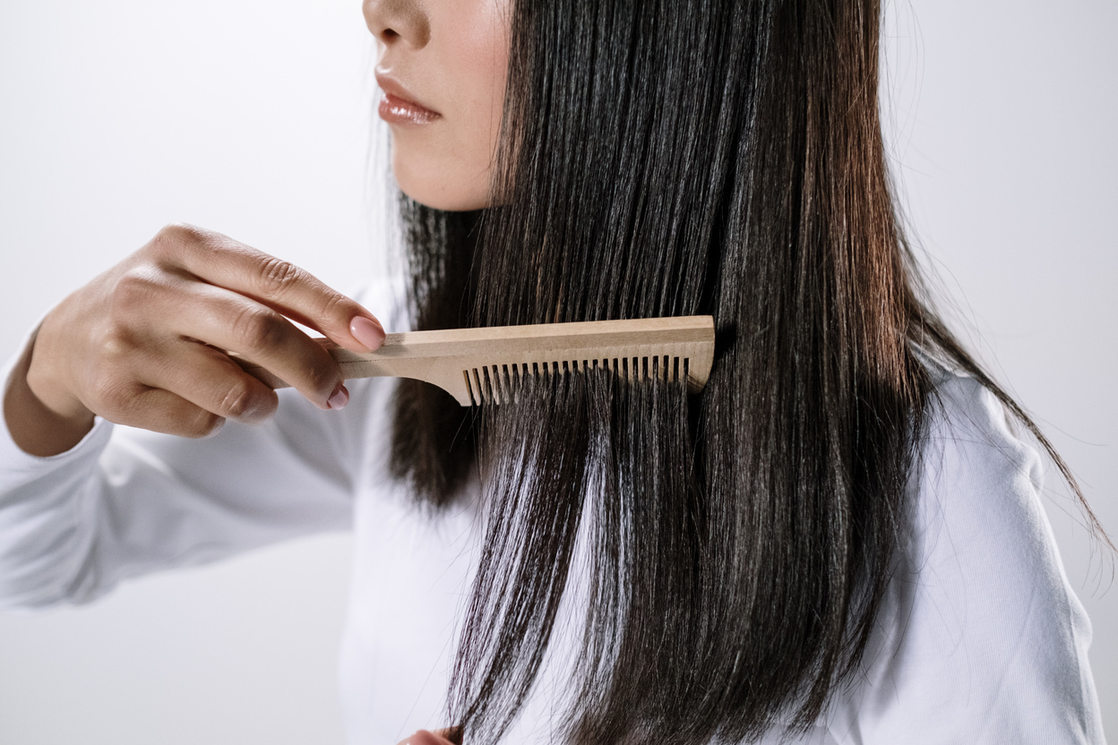 Woman Holding Brown Wooden Hair Comb